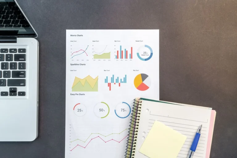 Marketing report printouts with charts beside a laptop