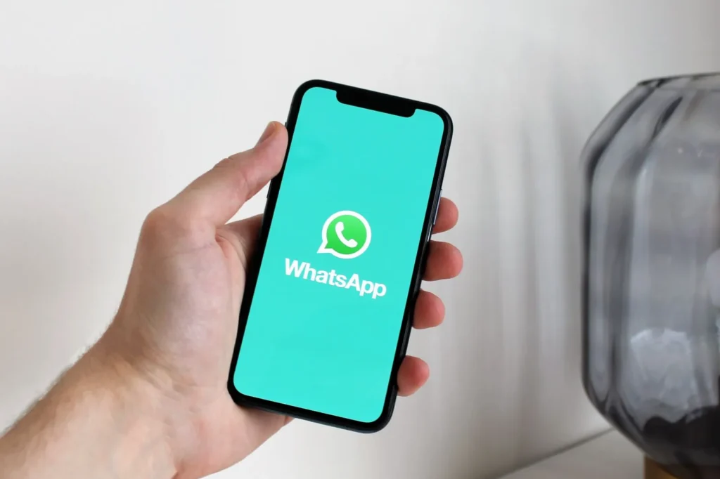 Hand holding a smartphone showing the WhatsApp app