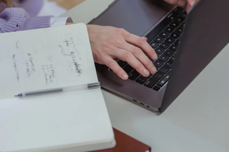 Content writer typing an article beside handwritten notes